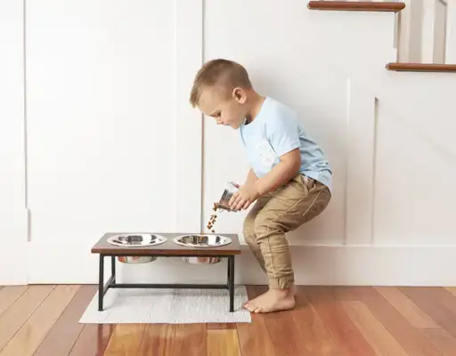Young child pouring dog food into a bowl