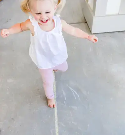 Young child walking on a line of chalk outside