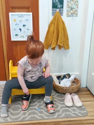 Toddler sitting on a stool putting on their shoes
