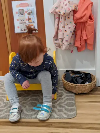 Toddler sitting on a stool putting on their shoes
