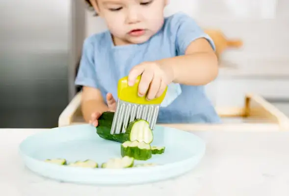 Toddler cutting up a cucumber