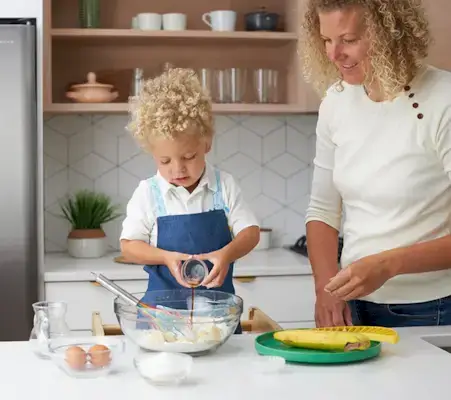 Toddler pouring vanilla into a mixing bowl 