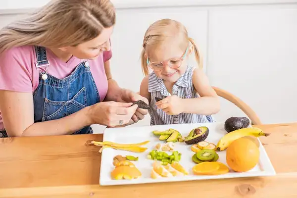 Woman and toddler looking at a tray filled with different fruits