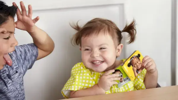 Toddler laughing at a young child making a funny face