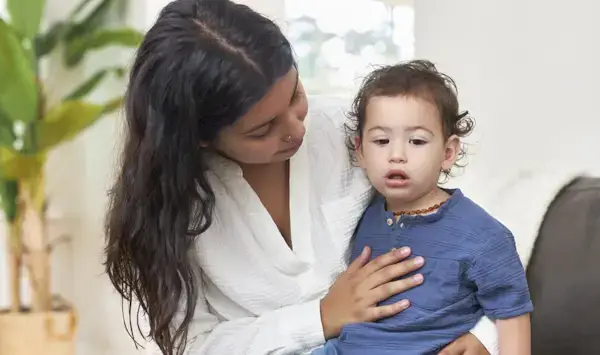 Woman holding a toddler on her lap while touching their chest