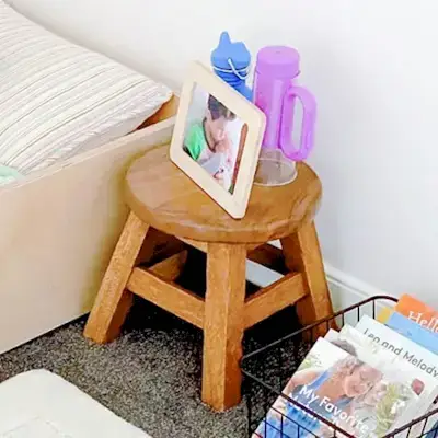 Wooden stool with picture frame and flashlight on it