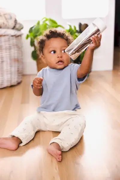 Child shaking a sensory bottle filled with sticks and rice