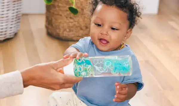 Child reaching for a sensory bottle filled with rubber bands