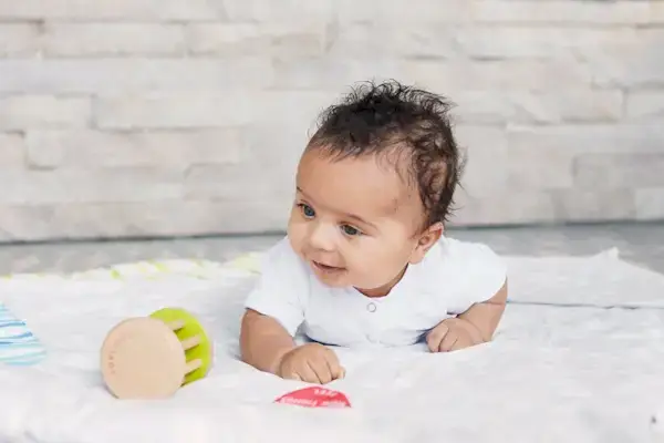 Baby doing tummy time and playing with the Rolling Bell from The Charmer Play Kit