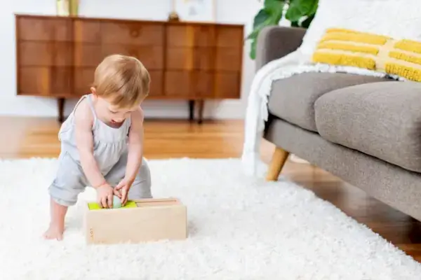 Baby dropping a ball into the Sliding Top Box from the Thinker Play Kit