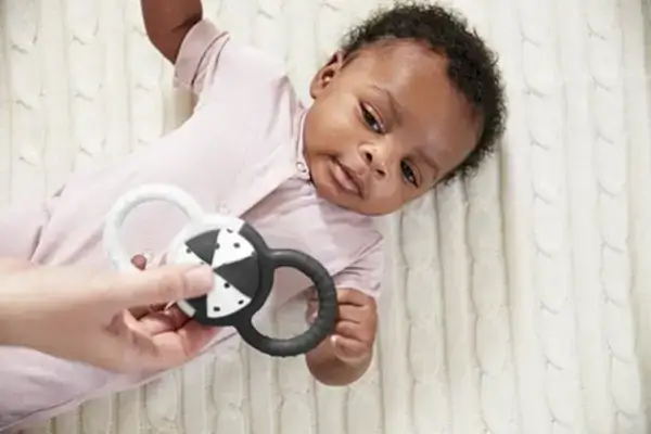 Baby laying on the ground looking up at Silicone Rattle with Removable Ball by Mommy's Reviews