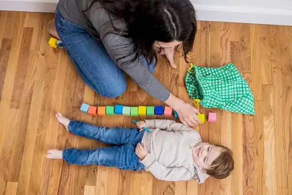 Toddler laying down on the ground next to a stack of blocks from The Block Set by Mommy's Reviews