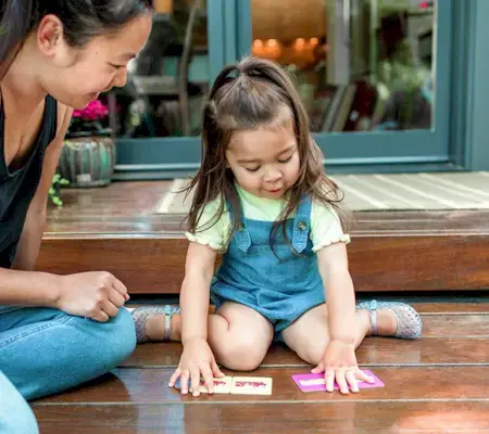Toddler sitting on the ground outside playing with the Memory Game cards by Mommy's Reviews
