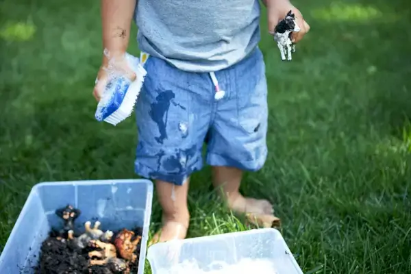Toddler playing outside and washing an animal figurine that was in dirt
