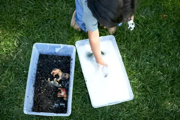 Toddler playing outside and washing an animal figurine that was in dirt