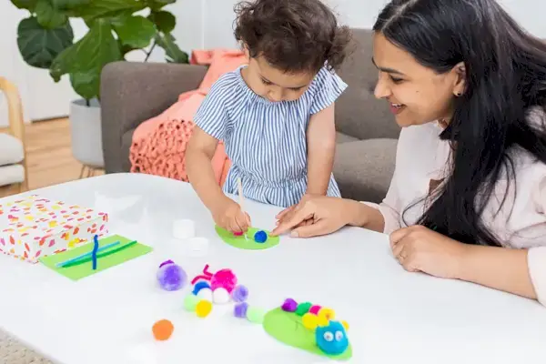 Toddler crafting with a woman at a table