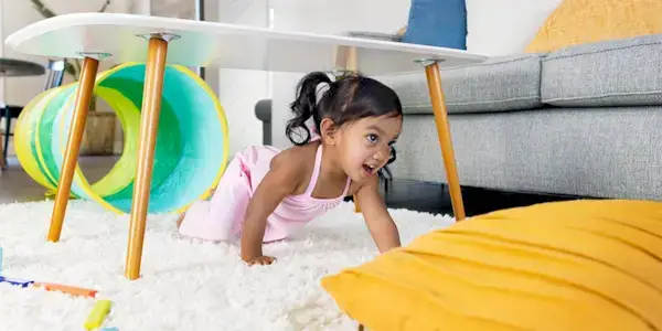Young child crawling under a table in a home made obstacle course with The Play Tunnel by Mommy's Reviews
