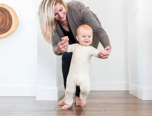 Baby walking while being supported by a woman