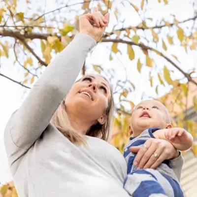 Mother holding their baby outside pointing at the sky