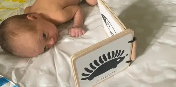 Baby doing tummy time and looking at the Wooden Book from The Looker Play Kit