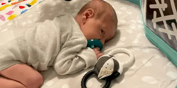 Baby laying on The Play Gym looking at Black & White Cards inside the Standing Card Holder from The Looker Play Kit