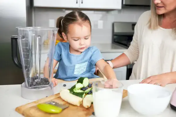 Toddler helping make a smoothie in the kitchen