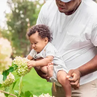 Baby touching a flower outside