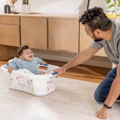 Little boy being pulled in a laundry hamper