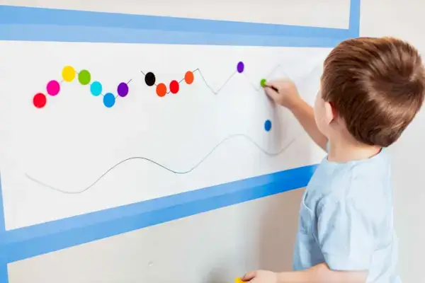 Young child putting stickers on a large piece of paper