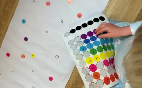 Young child putting stickers on a large piece of paper