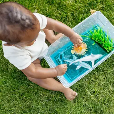 Child playing with fish toys in a bucket of water