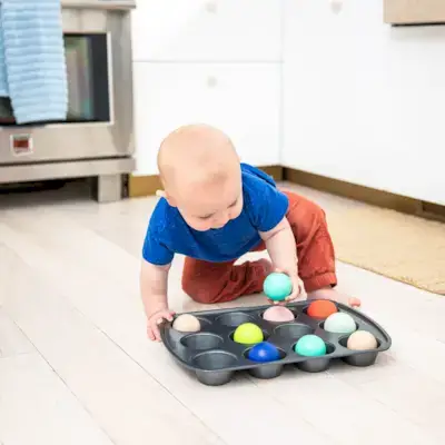 Child putting balls in a muffin tin