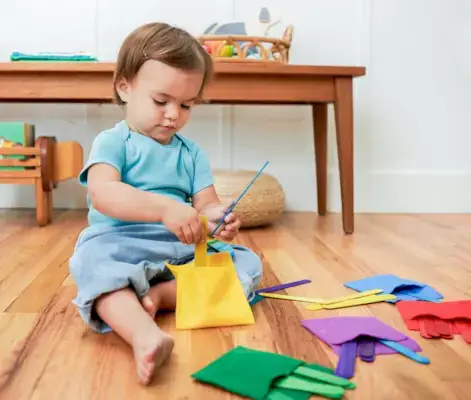 Toddler putting colored popsicle sticks into colored felt pockets