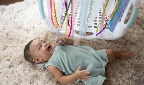 Baby looking up at streamers coming out of a laundry hamper