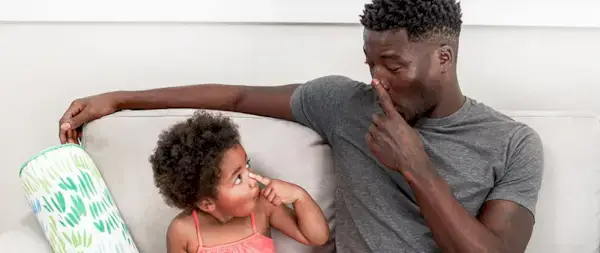 Toddler and man sitting on the couch both touching their noses