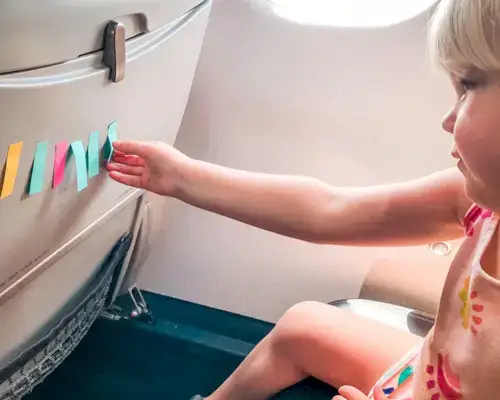 Child sitting in an air plane seat playing with post it notes