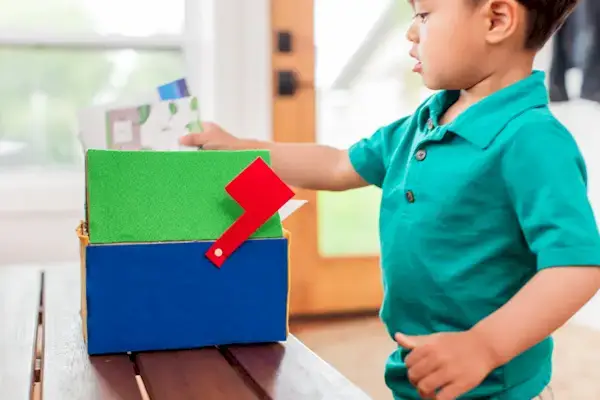 Young child putting mail in a DIY mailbox
