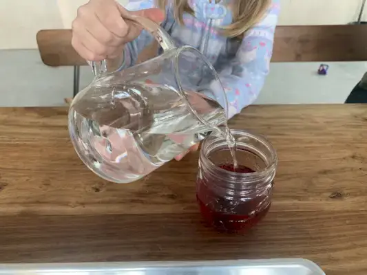 Child pouring water from a pitcher into a glass