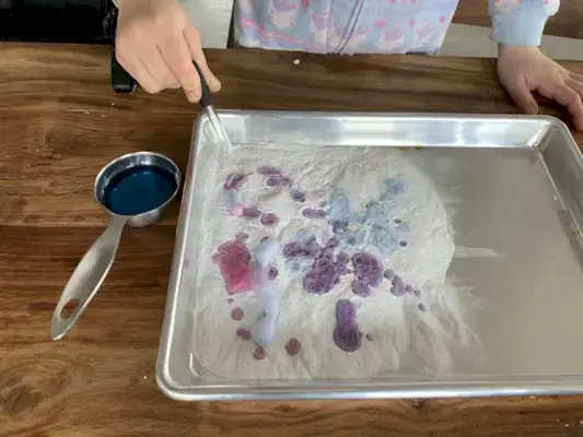 Tray of baking soda with a child dropping vinegar into it