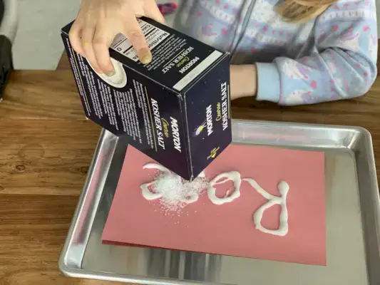 Child pouring salt on a piece of paper
