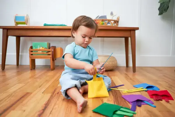 Child playing a color matching game with felt pockets and sticks