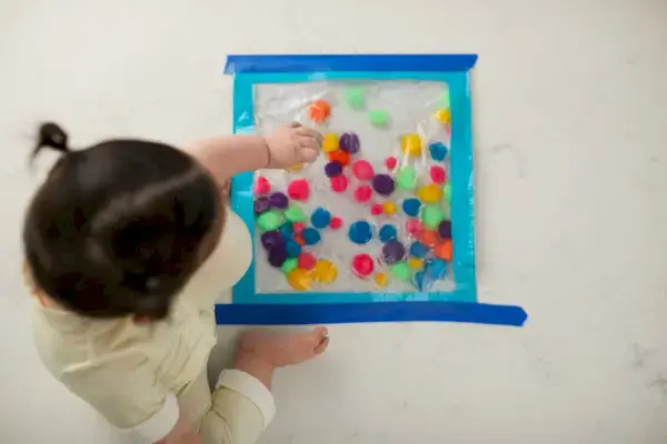 Child playing with a sensory bag filled with pom poms