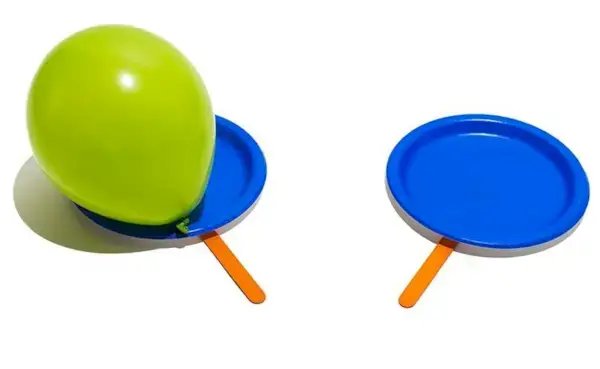 Green blown up balloon on a blue paper plate with a popsicle stick attached