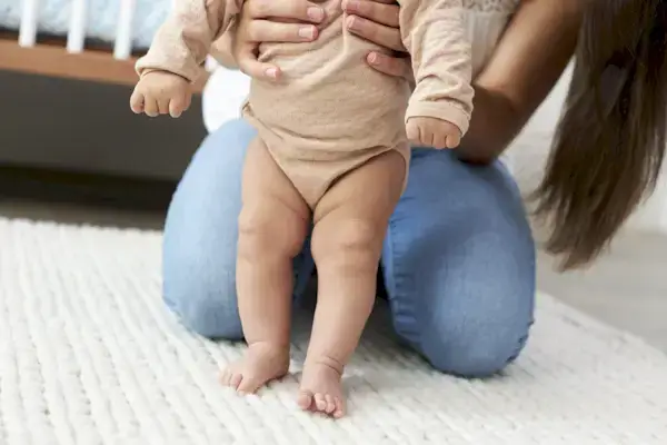 Woman holding a baby up and supporting them while they stand