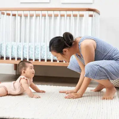 Baby doing tummy time while their mother is smiling and watching