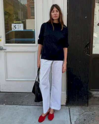 Lizzy Hadfield wears a black sweater, white cotton pants and red slippers while in New York.