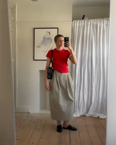 Brittany Bathgate wears leather slippers with a red top and beige balloon skirt.