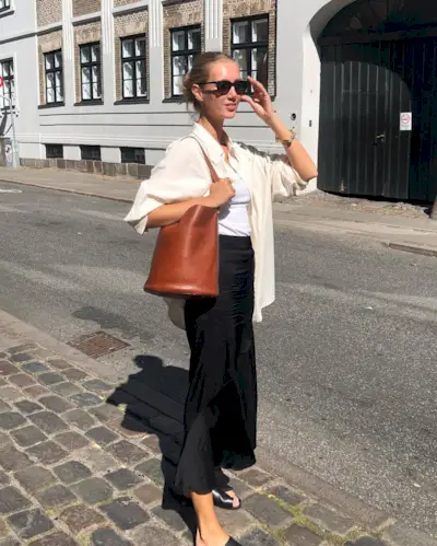 @amaliemoosgaard wears a satin skirt, tank top, linen shirt and sandals with a tan leather bucket tote