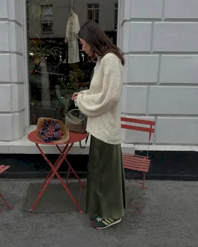 @francescasaffari wears a khaki satin skirt with green trainers and a cream jumper