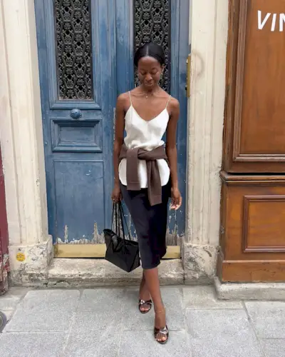 @sylviemus_ wears a black satin skirt with a white camisole and mules